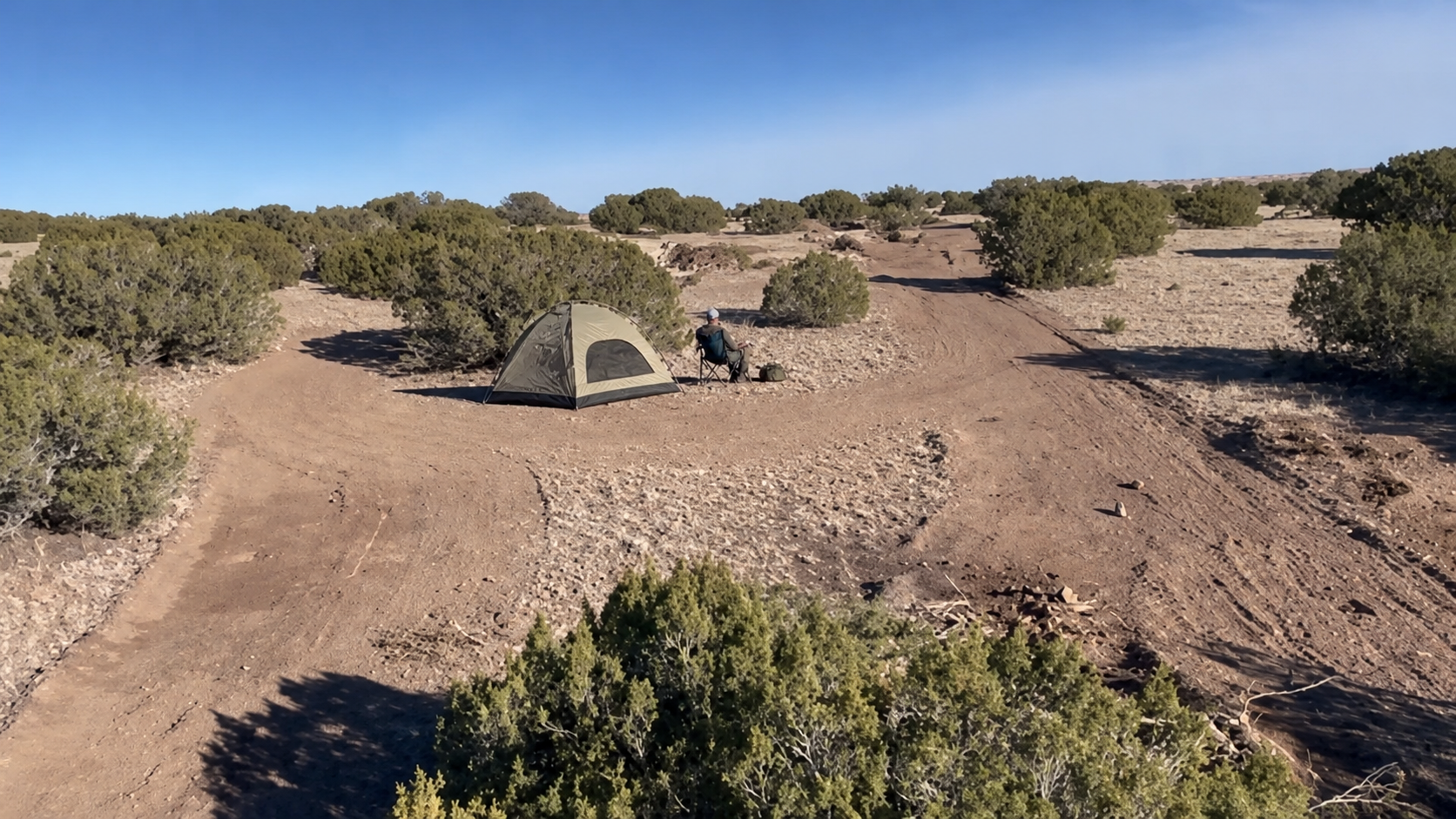 A guest enjoying a primitive tent campsite among the junipers at West End Ranch